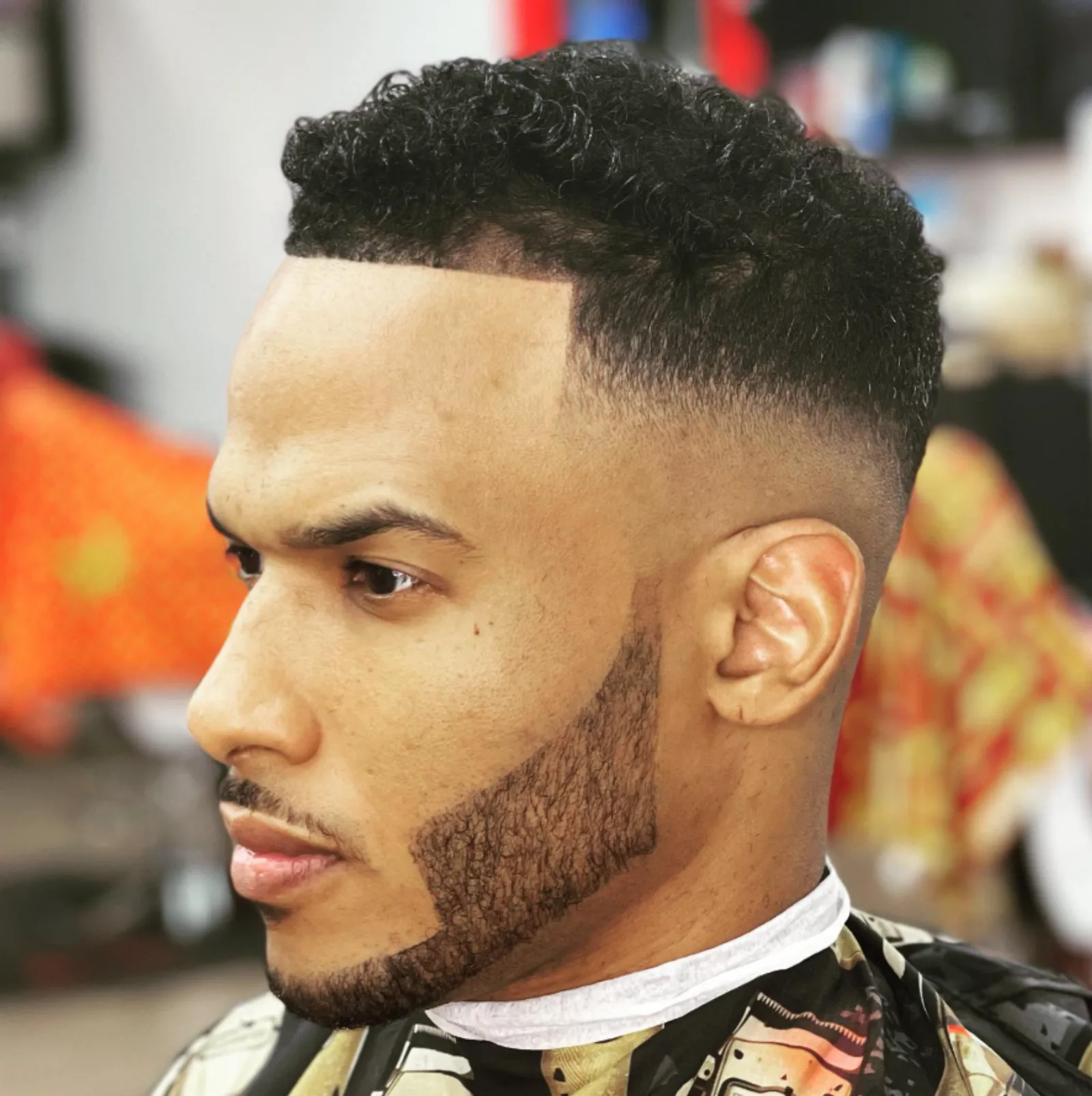 Customer with a tight curly top, mid skin fade, and crisp line-up