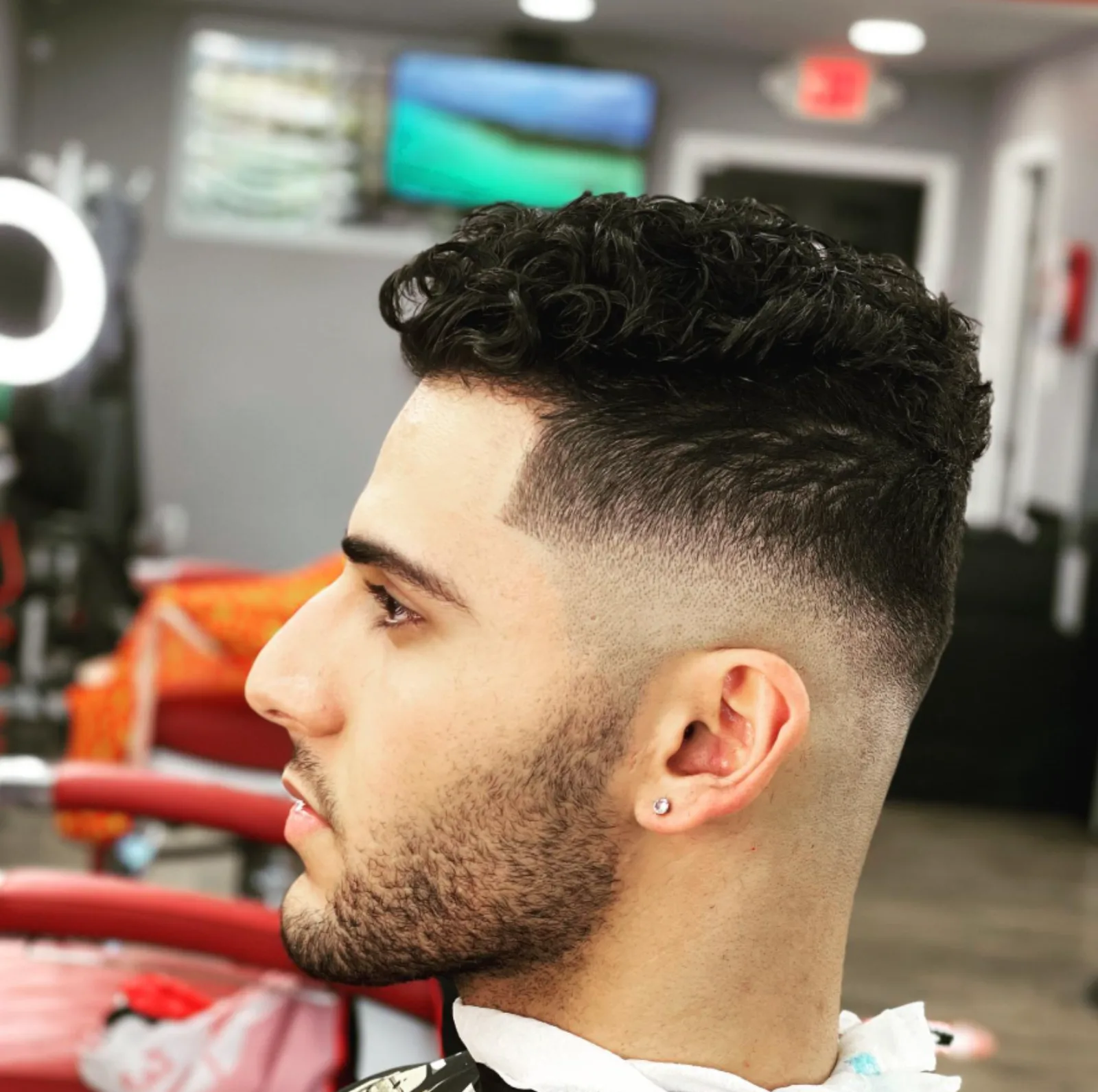 Curly textured top with a clean mid skin fade, side profile
