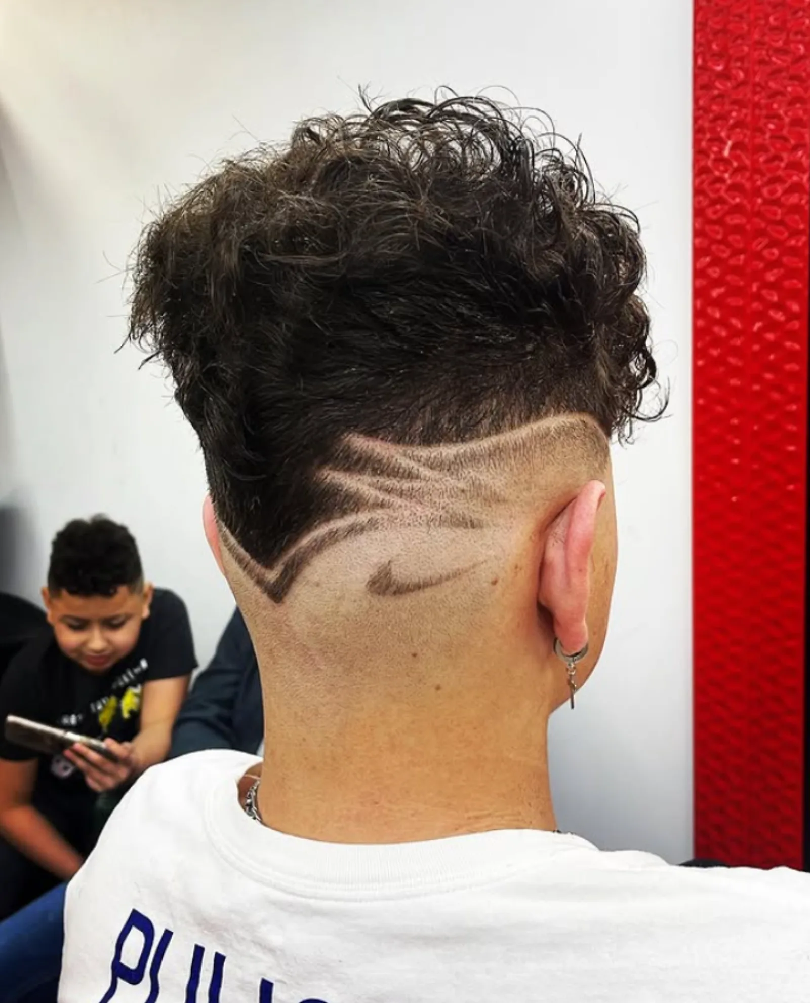Curly hair with a custom swoosh design carved into the fade